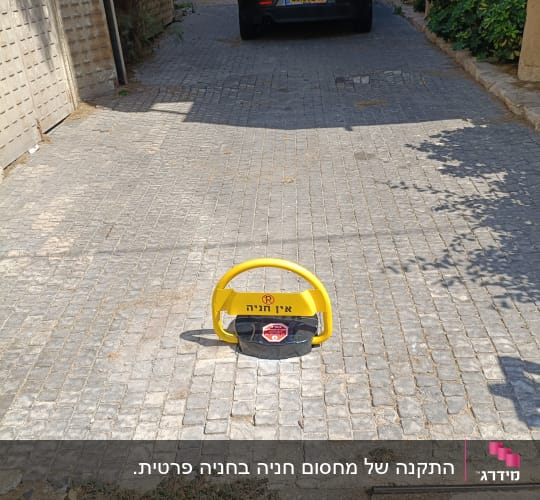 מחסום חניה אישי צהוב מותקן על ריצוף בכניסה לחניה פרטית